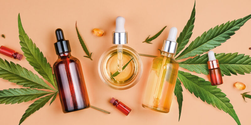 Different glass bottles with CBD OIL, THC tincture and cannabis leaves