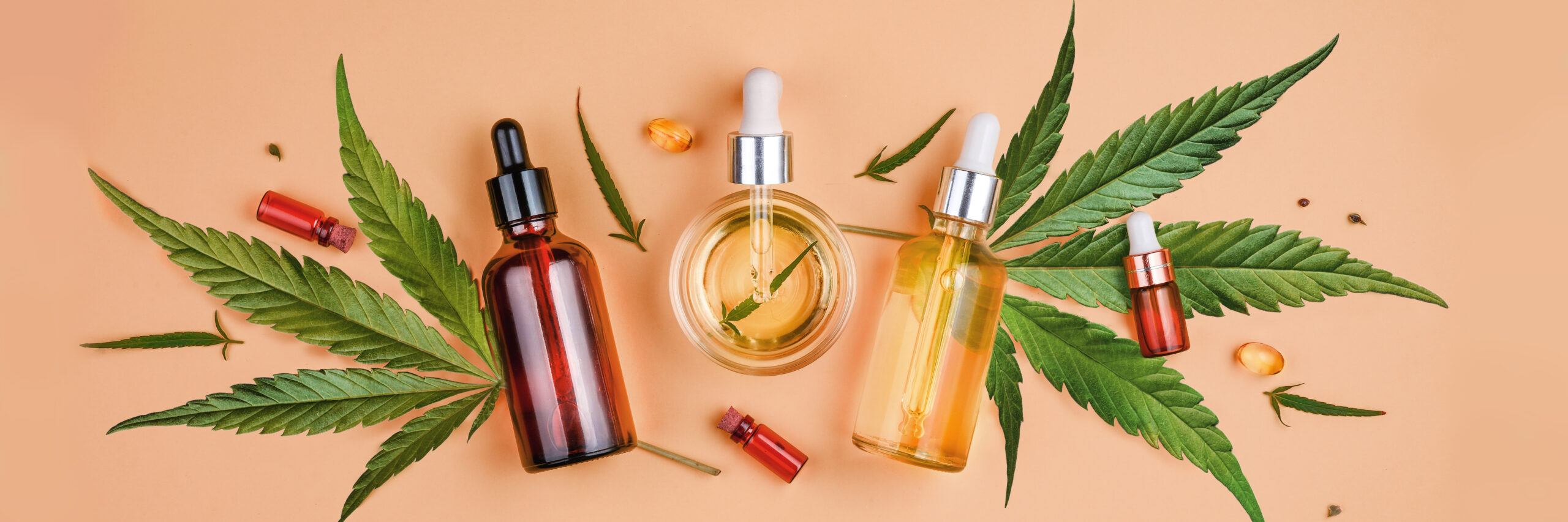 Different glass bottles with CBD OIL, THC tincture and cannabis leaves