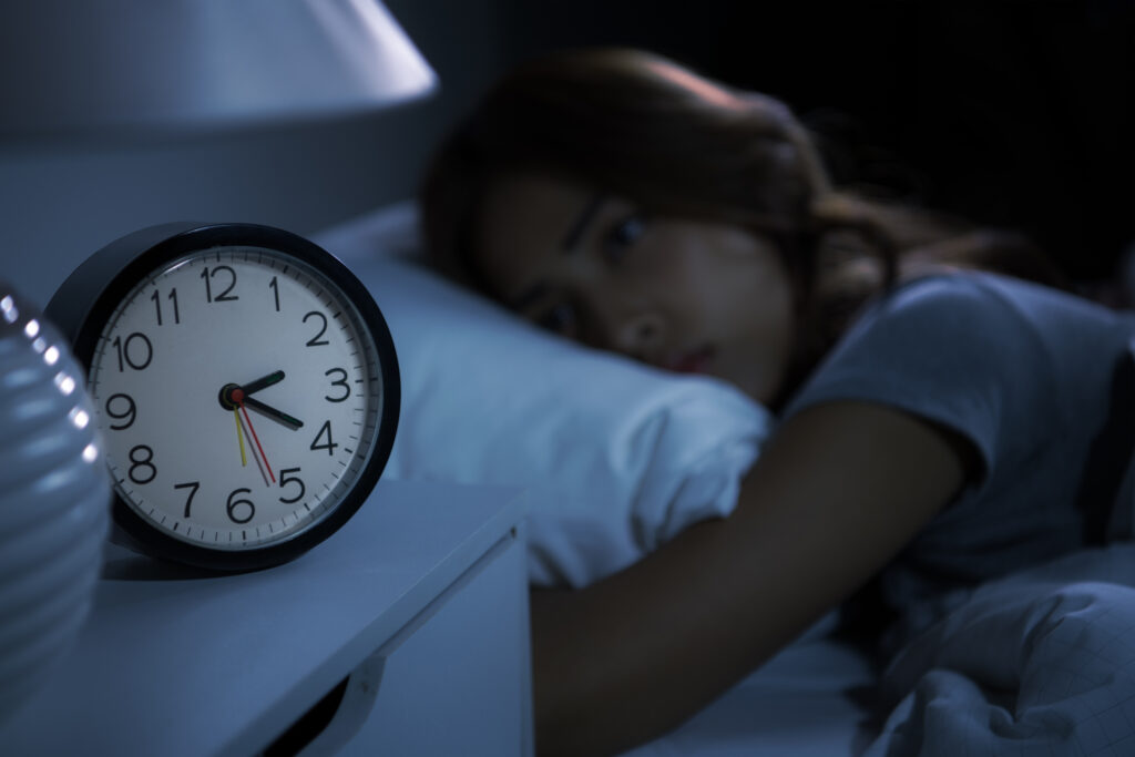 Depressed young woman lying in bed cannot sleep from insomnia