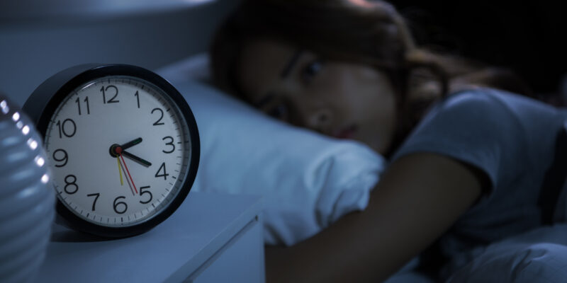 Depressed young woman lying in bed cannot sleep from insomnia